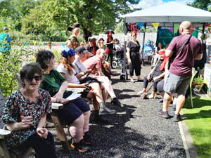 Large group of people sat in a sunny garden 