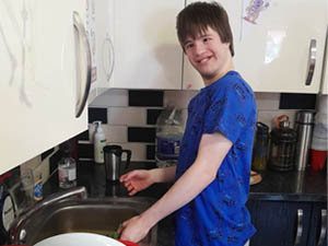 Boy in blue T-shirt washing up dishes