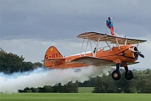 Lady in red jumpsuit doing a wing walk on an orange plane