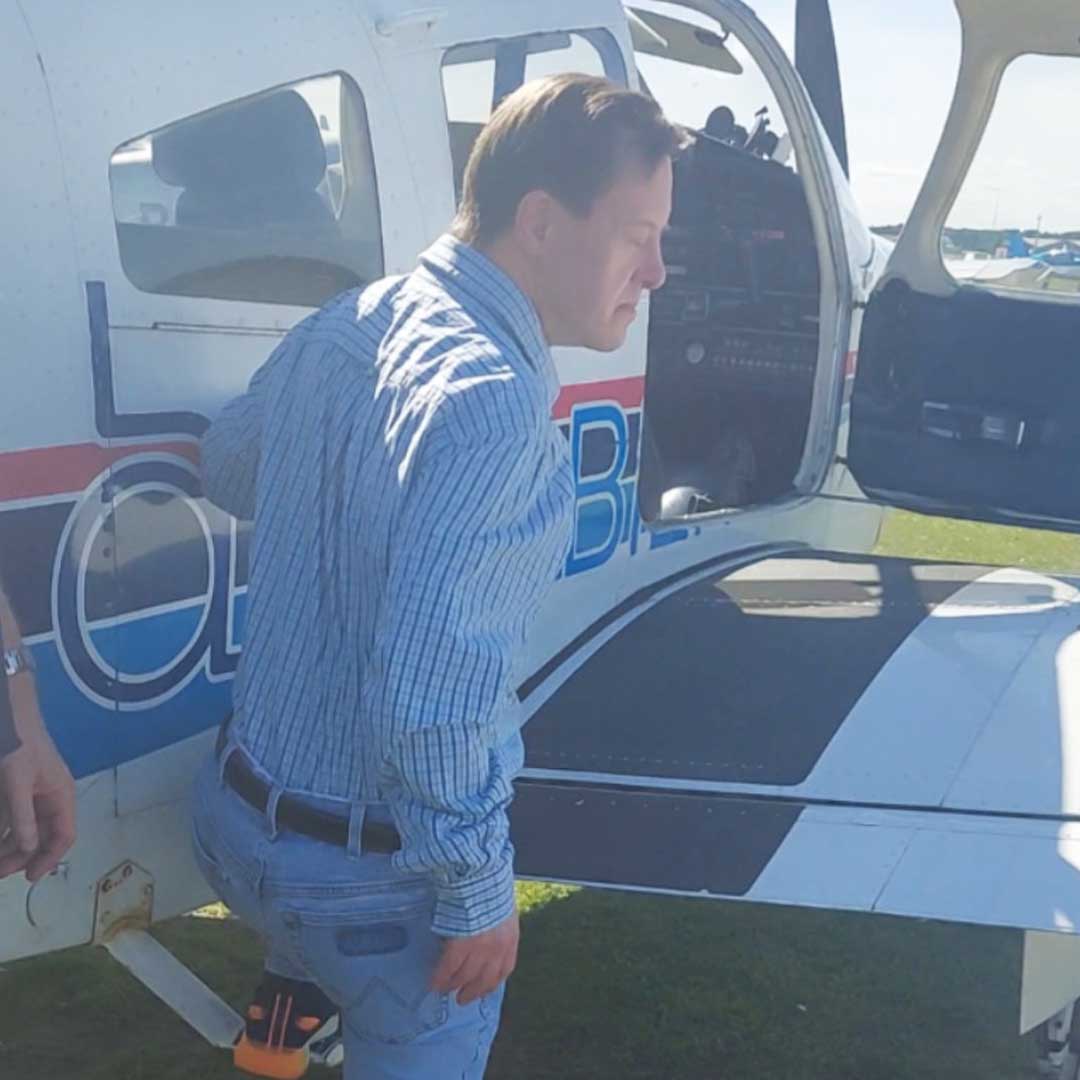 Man in blue shirt and jeans climbing into small plane