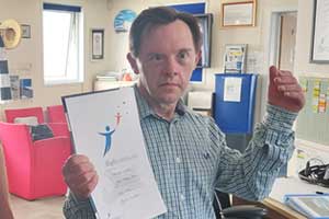 Man in blue shirt holding Aerobility flying certificate