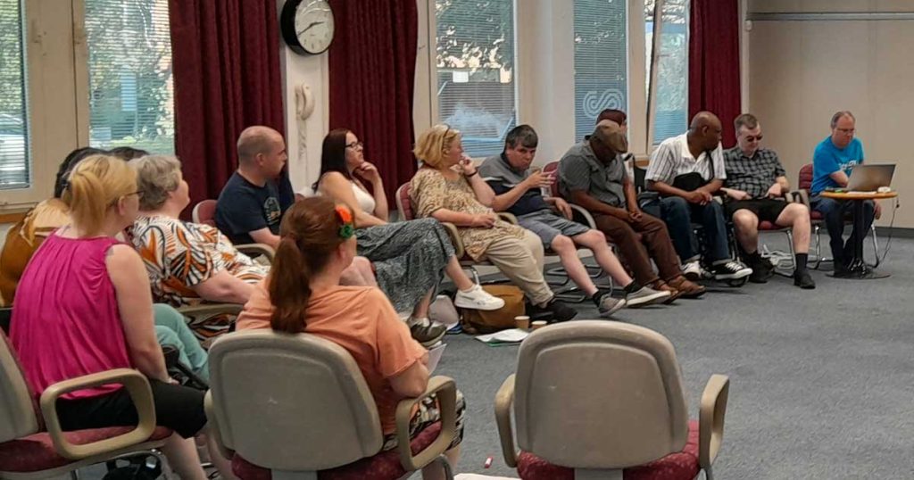 A group of people view a presentation on a large screen on the wall