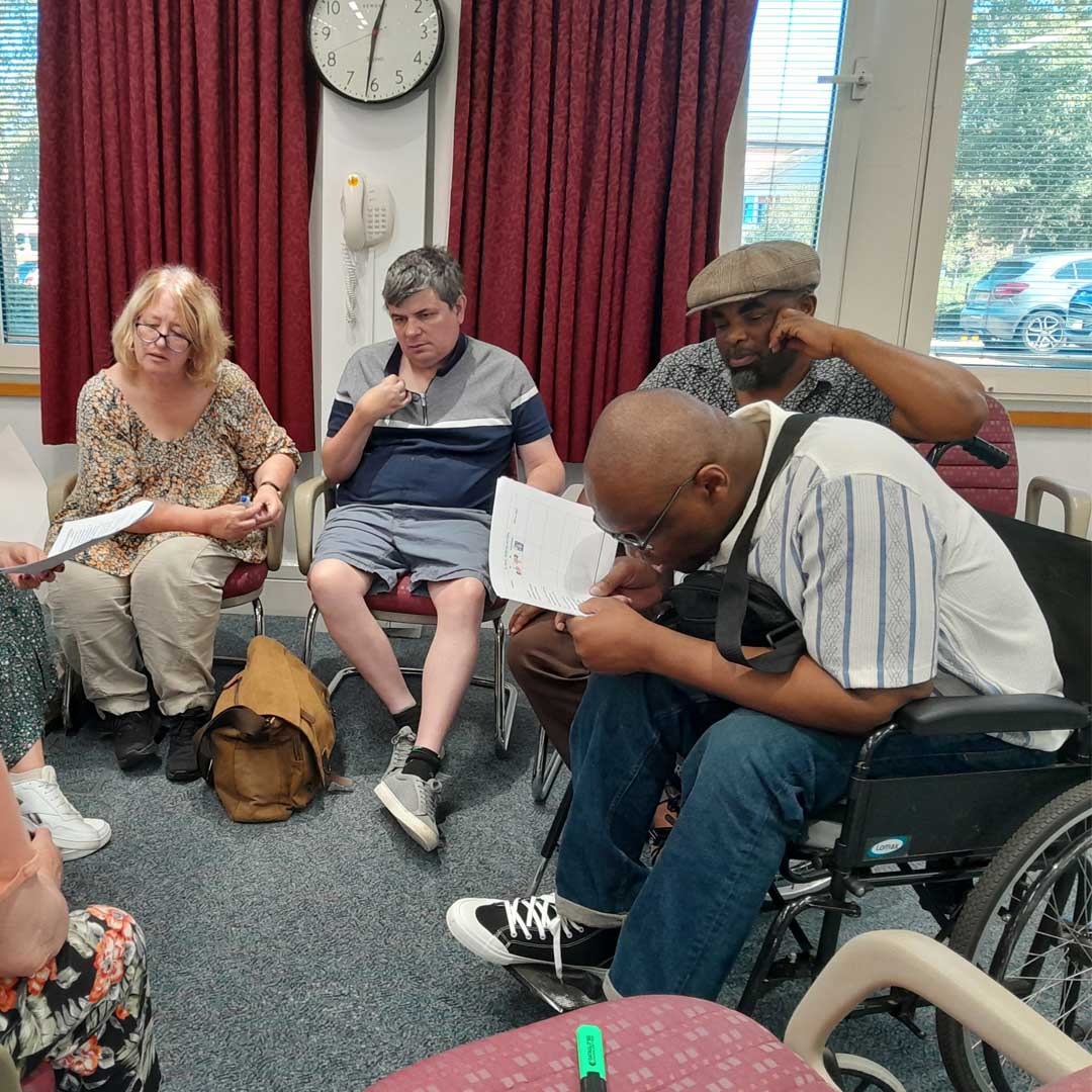 A group of people sat in a circle discuss a document