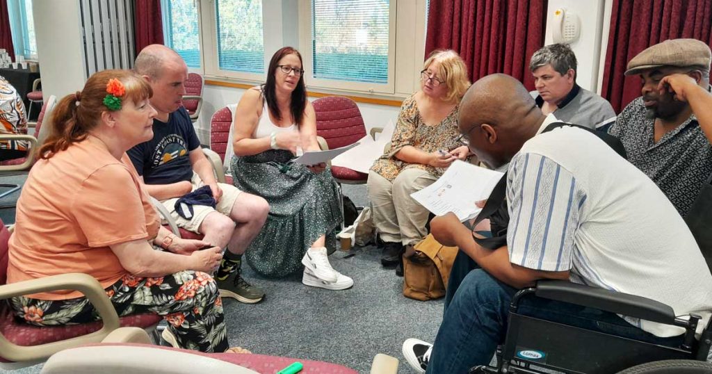 A group of people sat in a circle discuss a document