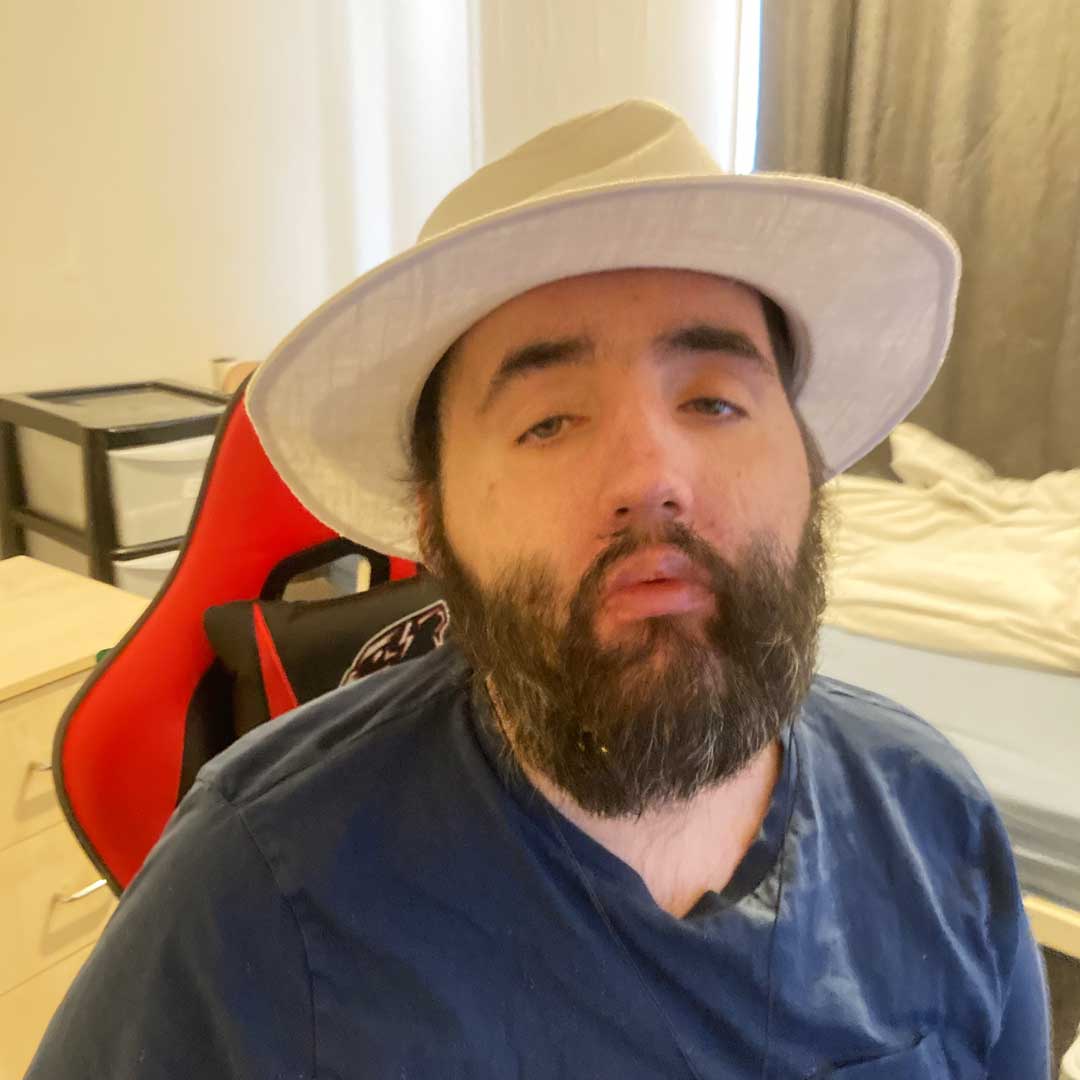 Man with beard wearing a blue top and a white panama hat