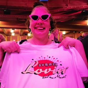 Woman wearing cat eye sunglasses holding up a T-shirt with a "summer lovin'" logo