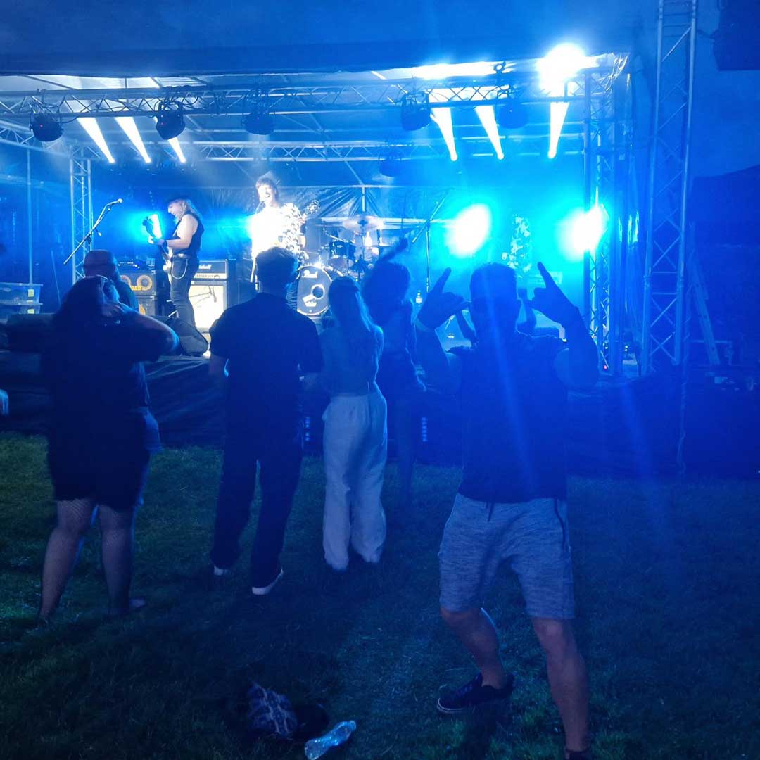 Group of people dancing in front of a stage backlit by blue spotlights