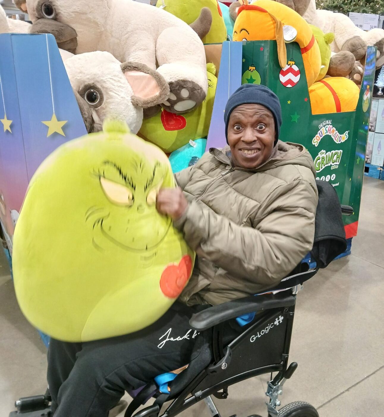 Devon smiling and showing a Grinch shaped pillow