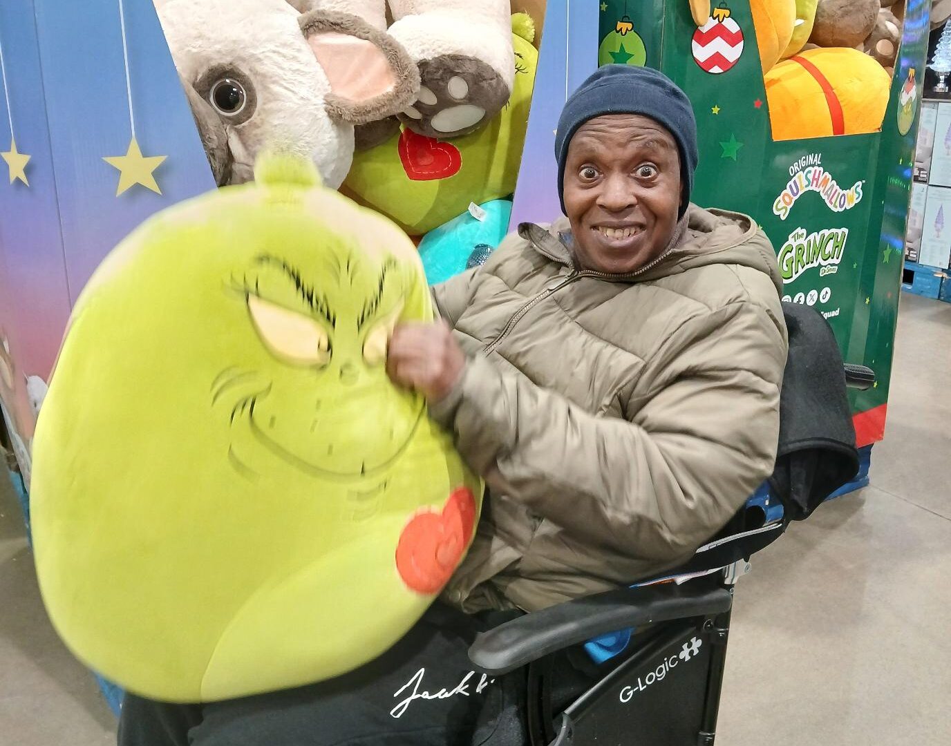 Devon smiling and showing a Grinch shaped pillow
