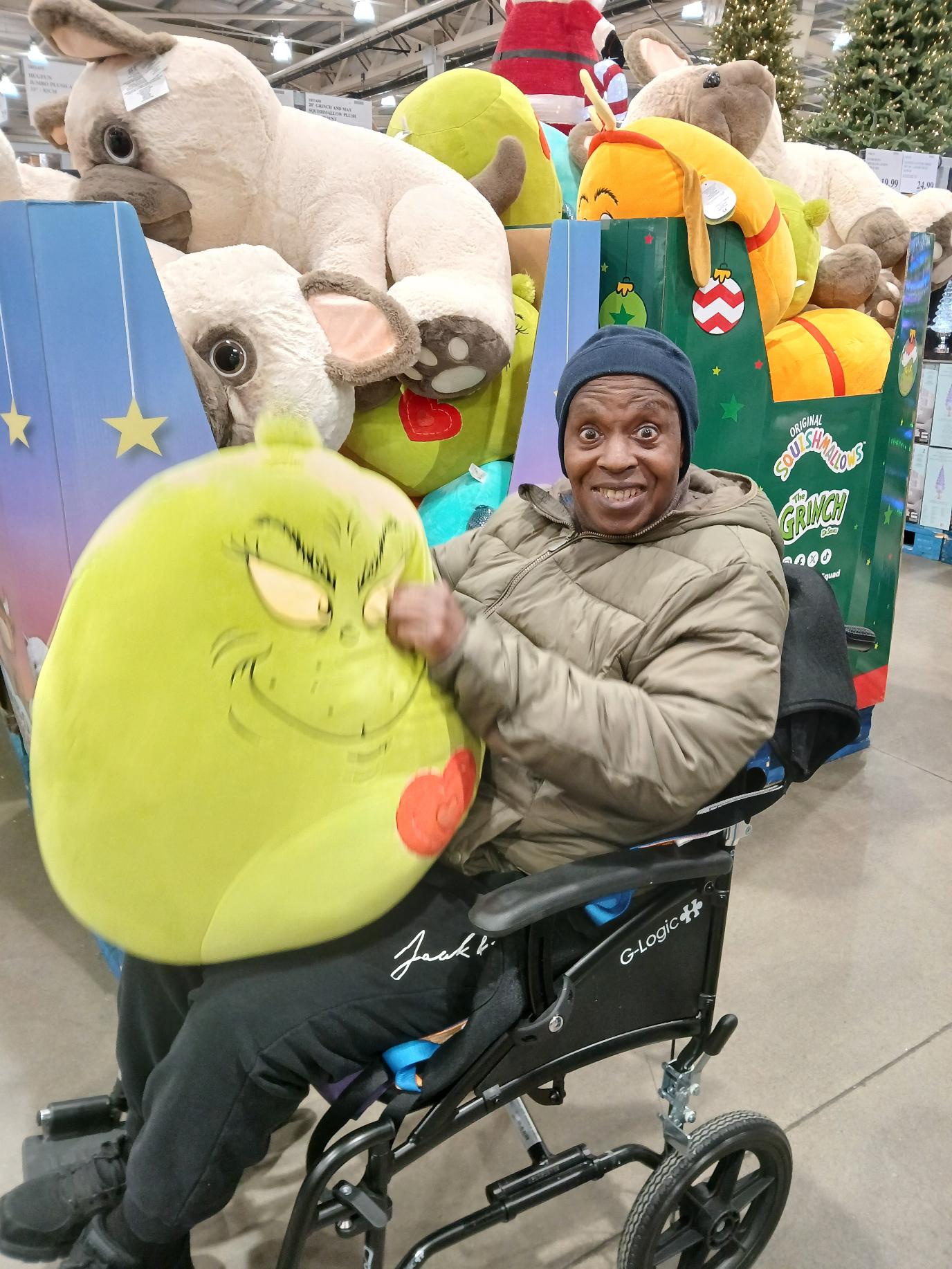 Devon smiling and showing a Grinch shaped pillow
