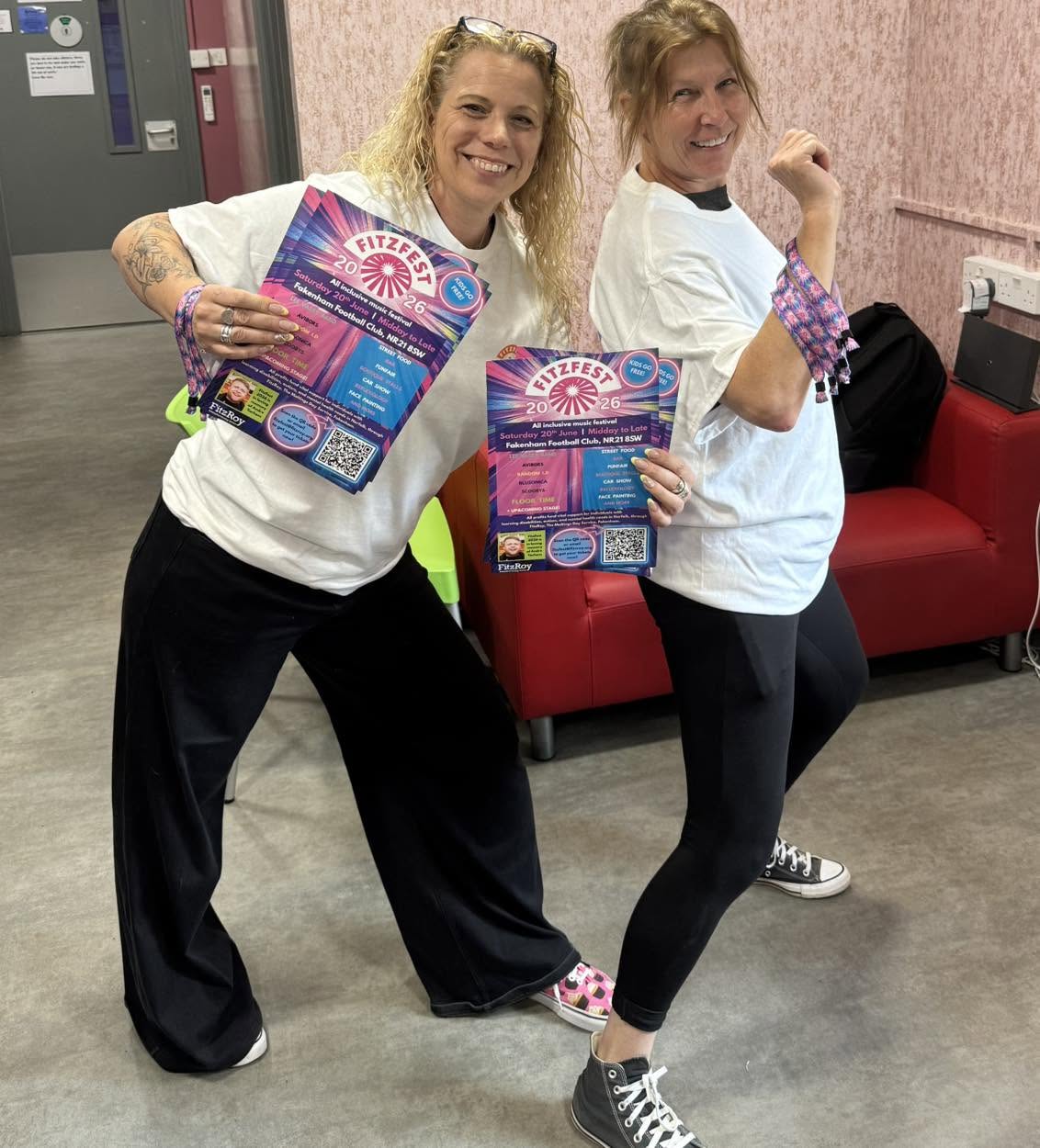 Kerensa and Rachel from The Maltings Day Service are posing with FizFest posters and merch.
