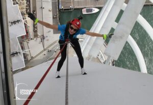 Zoe looks up with her arms outstretched while abseiling down Portsmouth’s Spinnaker Tower, attached to safety ropes.